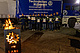 THW-Helfer mit Urkunde vor blauem LKW bei Nacht mit Feuertonne